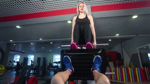 Man focused on training legs on the machine in the gym with trainer Vídeos de archivo 73231190