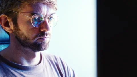 Man focused on work watching computer screen at nighttime home office Stock Footage 318214059