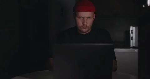 The man is focused working on a laptop in a dark room of the apartment Stock Footage 302900466