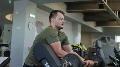 Man focusing on strength training doing bicep curls on a fitness machine Stock Footage 339598561