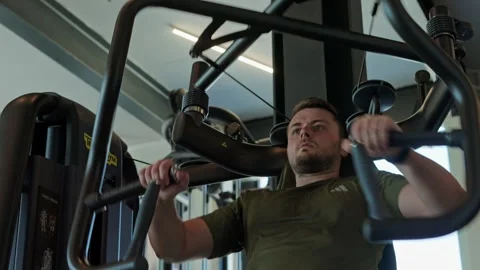 Man focusing on strength training using a chest press machine Stock Footage 339598998