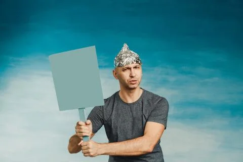 A man in a foil hat scaredly grabs his hands with his hands wide open his eye Stock Photos