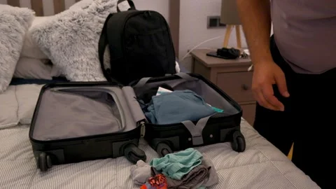 Man folding and packing clothes into a suitcase for a journey Stock Footage 334953796