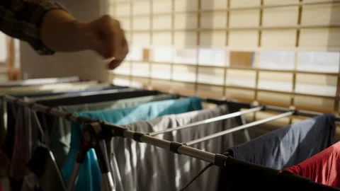 Man folding and taking dry clothes off a drying rack. Close-up of a man car.. Vídeos de archivo 332162351