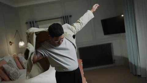 A man is folding a bed sheet in a hotel room Stock Footage 295996646