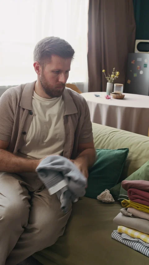 Man Folding Clothes in Perfect Stacks While Doing Housework Stock Footage 316821963