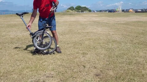Man folds up a Brompton folding bicycle, carries it away Stock Footage 244325460