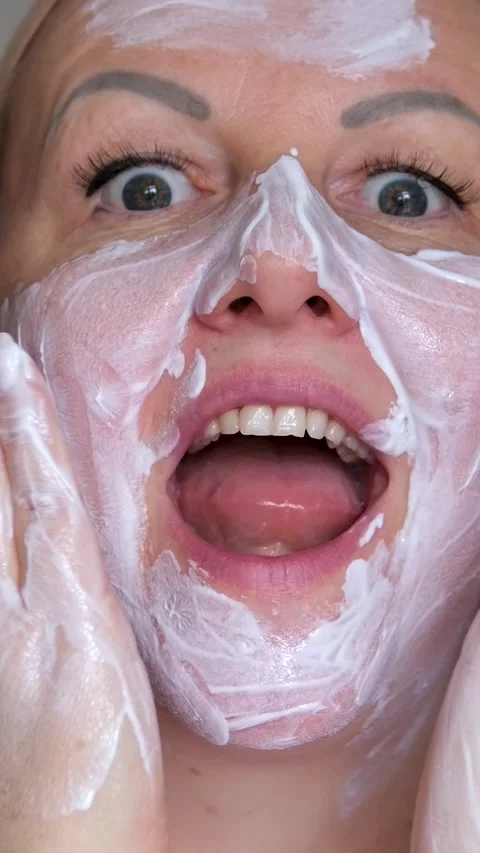 Man fooling around using white cream face mask. sleek eyes funny and sloppy Stock Footage 293692709