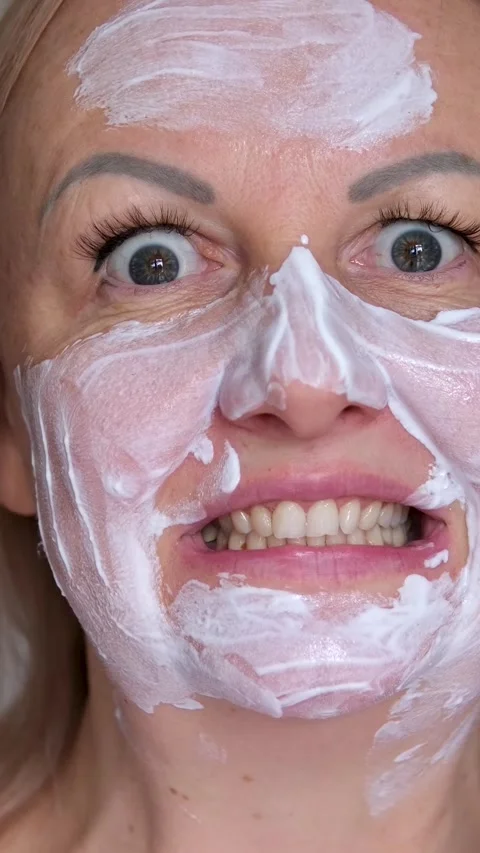 Man fooling around using white cream face mask. sleek eyes funny and sloppy Stock Footage 293692954