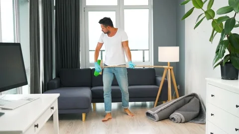 Man fooling around while cleaning the house and imagines himself a rock star Stock Footage 201267589
