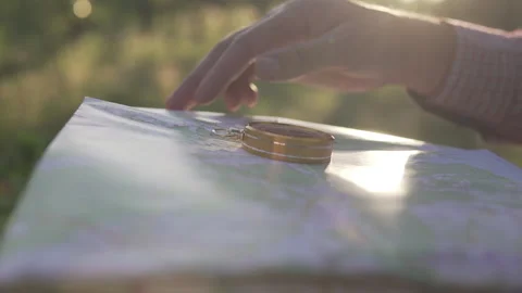 A man in the forest with a compass and a map in his hand on a sunset background 库存影片 134801866