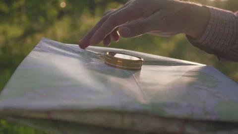 A man in the forest with a compass and a map in his hand on a sunset background Stock Footage 134801923
