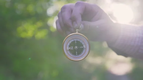 A man in the forest with a compass in his hand on a sunset background Stock Footage 134801690