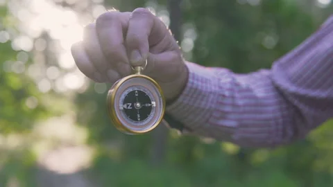A man in the forest with a compass in his hand on a sunset background Stock Footage 134801703