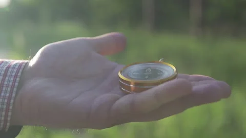 A man in the forest with a compass in his hand on a sunset background Stock Footage 134801761