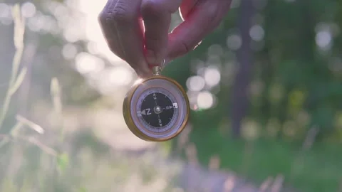 A man in the forest with a compass in his hand on a sunset background Stock Footage 134801774