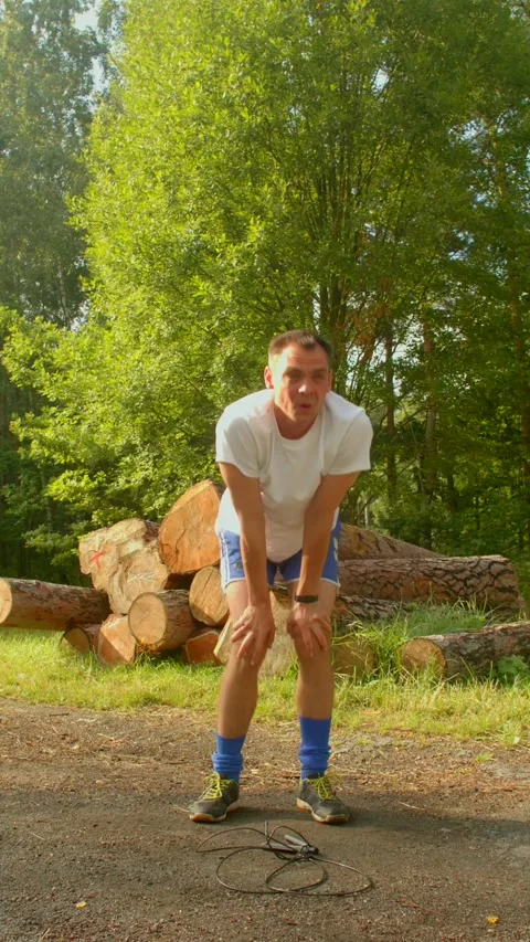 A man in a forest examines logs, reflecting on natures beauty Stock Footage 314345806