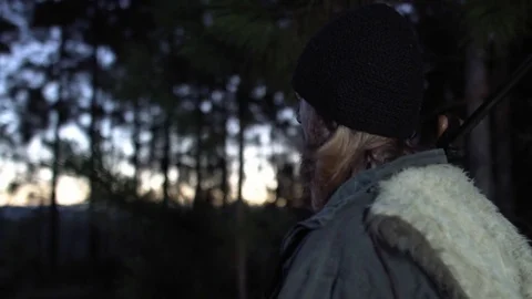 Man in a forest holding a gun looking at the horizon at dawn. Stock Footage 76444278