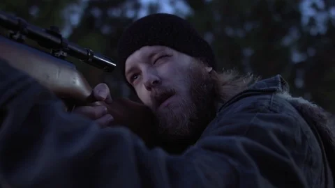 Man in a forest looking to the horizon and aiming a gun. Stock Footage 76474167