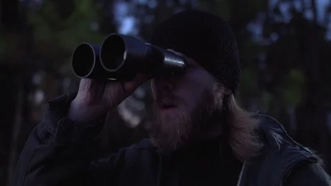 Man in a forest looking to the horizon with binoculars at dawn. Stock Footage 76473340