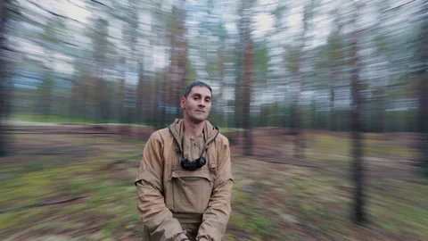 A man in the forest is spinning in a circle while standing in one place. Видео 342538681