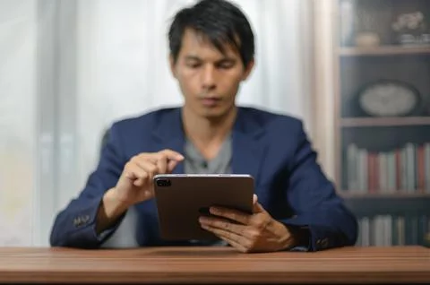 Man in formal attire using tablet computer at home or office setting Photos