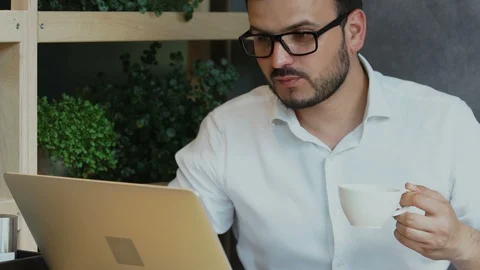 Man in formal clothes holding cup of coffee and looking to the screen of his Stock Footage 112989330