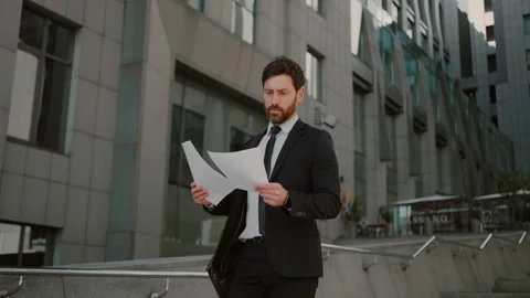 Man in formal clothes reads documents walking down stairs Stock Footage 246018431