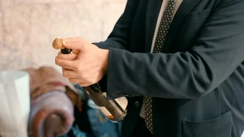 A man in a formal suit opens a bottle of champagne. Stock Footage 229529650