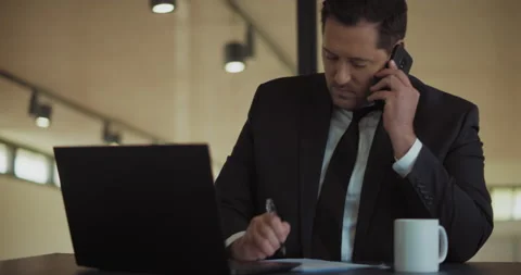 A man in a formal suit working on a computer and signing some documents Stock Footage 140204304