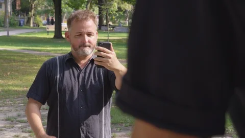 A man frames up a picture of his friend at the park - shot on RED Stock Footage 124717906