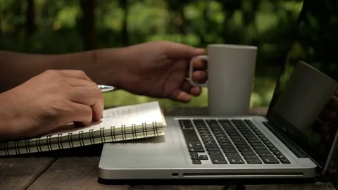 A man freelancer designer use laptop, writing on notebook and drinking coffee Stock Footage 70565202
