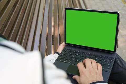 Man freelancer holding black tablet pc with mock up green desktop screen sitt Stock Photos