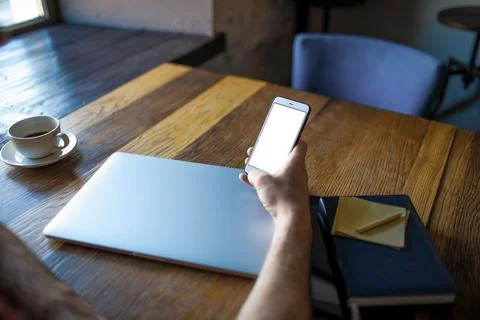 Man freelancer holding in hand mobile phone with white empty copy space scree Stock Photos