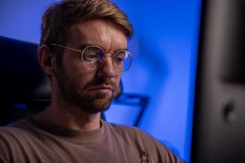 Man freelancer at remote work at home office late night focused blue lighting Stock Photos
