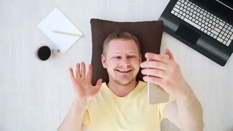 Man-freelancer talking on video communication smartphone at home on the floor Stock Footage 91188586