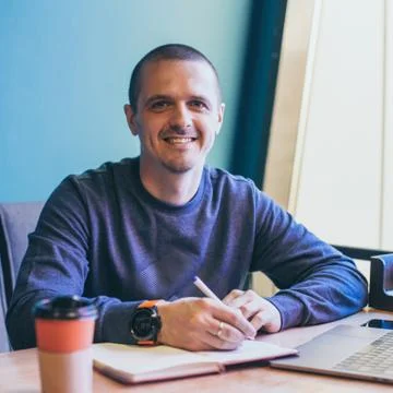 Man freelancer working in cafe and writing some notes in notebook Stock Photos