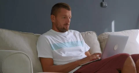 Man freelancer working on computer laptop at home on comfortable couch. Stock Footage 246399276