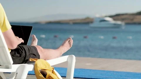 Man freelancer working online remotely using laptop sitting on deck chair with Stock-Footage 231599511