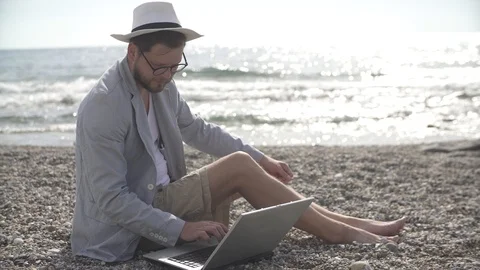 Man freelancer working remotely on the beach of the sea Stock Footage 125777809