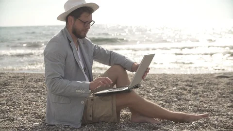 Man freelancer working remotely on the beach of the sea Stock Footage 125778640