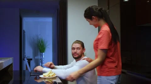 A man freelancer works from home on a computer, his wife brought food for him, a Stockbeeldmateriaal 267417227
