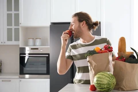 Man with fresh products near modern refrigerator in kitchen Stock Photos