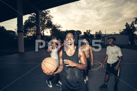 Man With Friends On Basketball Court Holding Basketball Smiling