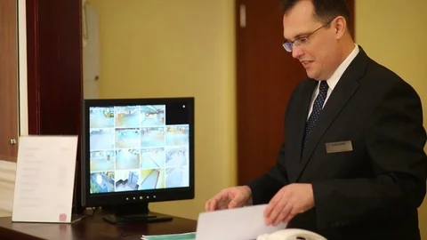 Man at the front desk leafing through a folder with documents Stock Footage 70953956
