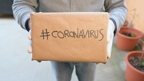 Man at the front door hands a package with coronavirus written on it Stock Footage 127584835