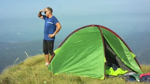 Man In Front Of His Tent On The Top Of The Mountain Looking What He Overcame Stock Footage 93661452