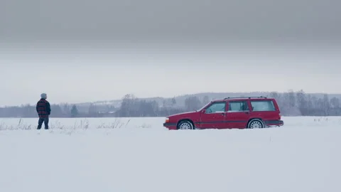 Man in front of idling red car with gases escaping exhaust in snowy landscape 스톡 동영상 331035909