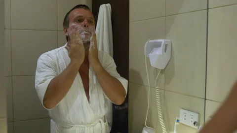 The man in front of a mirror causes shaving foam and shaves machine Stock Footage 91327142