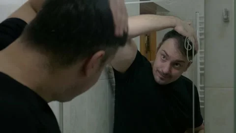 Man in front of a mirror gets nervous when he can’t style his hair Stock Footage 268224236